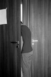 Rear view of man standing against door at home