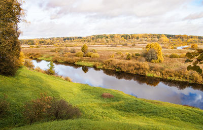 Picturesque autumn landscape with trees, river and sky.