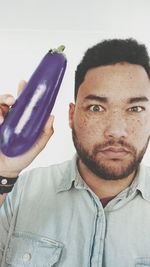 Portrait of serious mid adult man holding eggplant