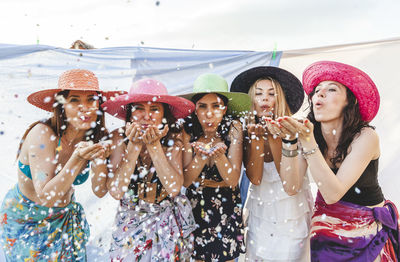 Portrait of friends blowing confetti on rooftop