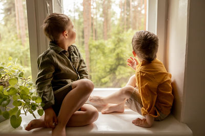 Children sitting on windowsill and waiting for someone comming. two brothers, friends 