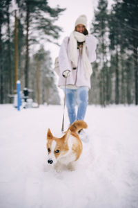 Portrait of woman with dog on snow covered field