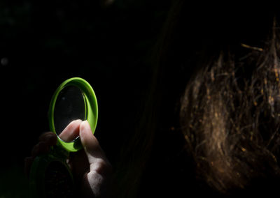 Close-up of hand holding leaf against black background