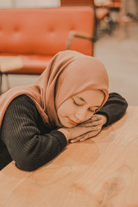 Portrait of young woman sleeping on table