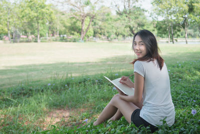 Young woman smiling while sitting on field