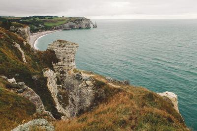 Scenic view of sea by cliff against sky