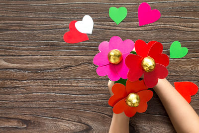 High angle view of person holding red heart shape on table