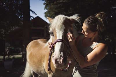 Side view of woman with horse against black background