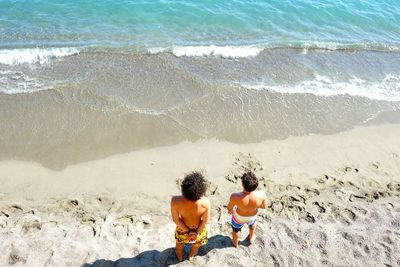 High angle view of friends standing on beach