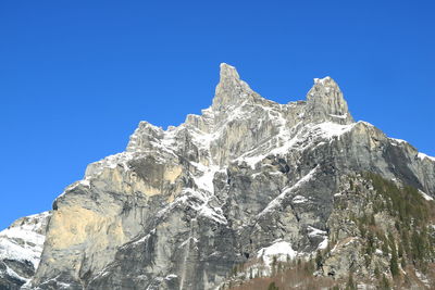 Low angle view of snowcapped mountain peak against clear blue sky