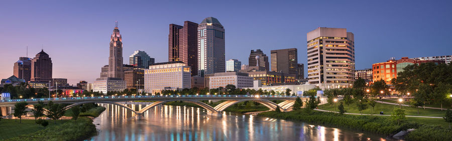 Bridge over river by buildings against sky in city