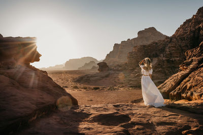 Woman standing on sand dune in desert against clear sky