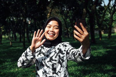 Young man using smart phone while standing on tree