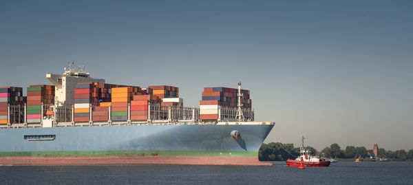 Container ship on the river elbe with a tugboat while parking