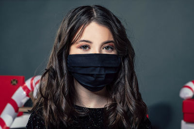 Portrait of girl wearing mask against black background