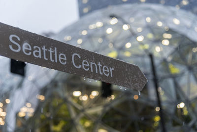 Low angle view of illuminated text on wet sign