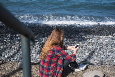 High angle view of woman using phone at beach