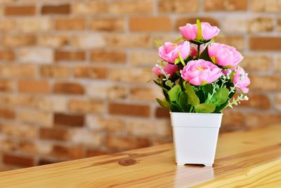 Close-up of pink flower vase on table against wall