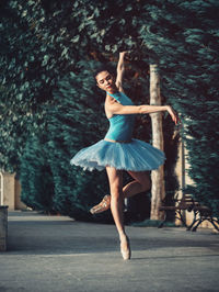 Ballet dancer dancing on footpath against trees