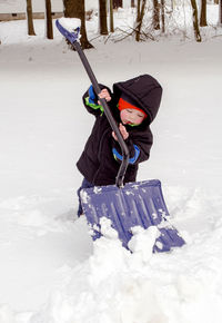 Small boy uses a big shovel to try and shovel snow