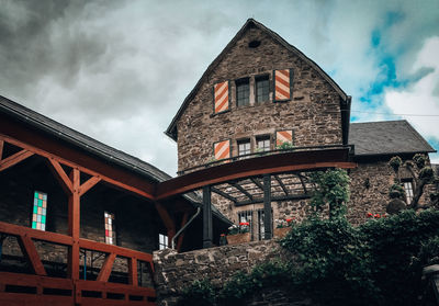 Low angle view of house by building against sky