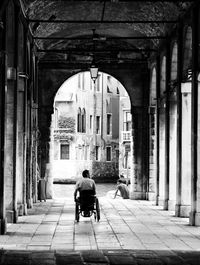 Rear view of disabled man on wheelchair in corridor