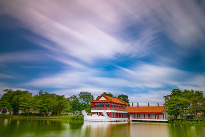 View of building by lake against cloudy sky