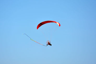 Low angle view of person paragliding against clear blue sky