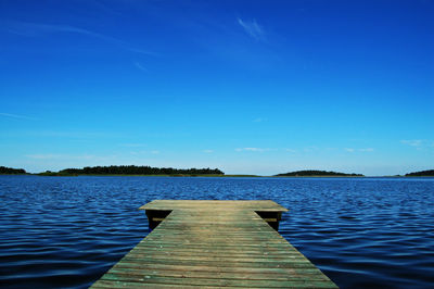 Pier over lake against blue sky