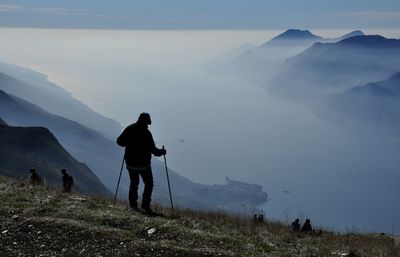 Rear view of men standing on mountain against sky