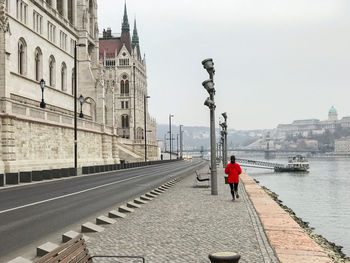 Rear view of man walking on street against buildings