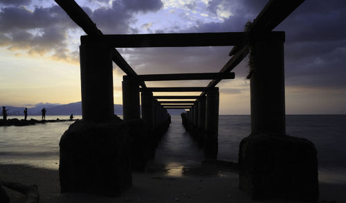 Silhouette pier over sea against sky during sunset