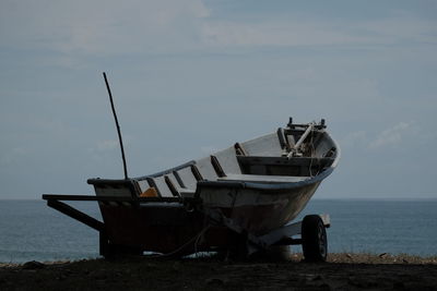 Fishing boat on beach against sky