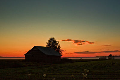 House on field against sky during sunset