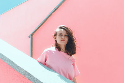 Portrait of woman standing against pink wall