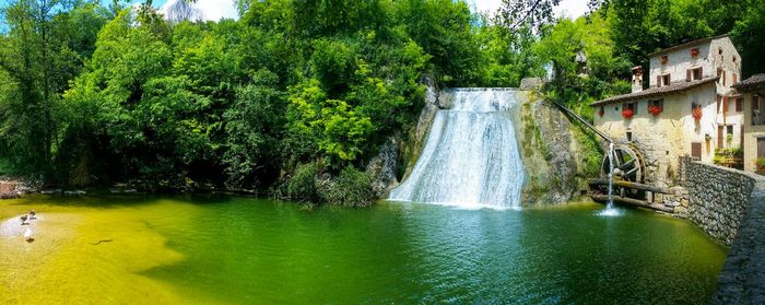 Scenic view of waterfall in forest against sky