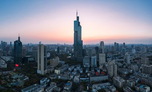 Modern buildings in city against sky during sunset