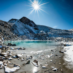 Scenic view of frozen lake against bright sun