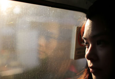 Close-up of woman looking through window in train