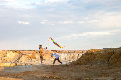 Rear view of man standing on rock against sky