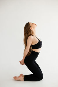 Portrait of young woman standing against white background