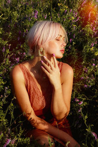 Midsection of woman sitting by flowering plants