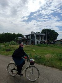 Man riding bicycle by plants against sky