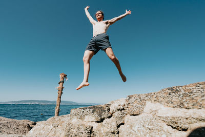 Low angle view of woman jumping on beach