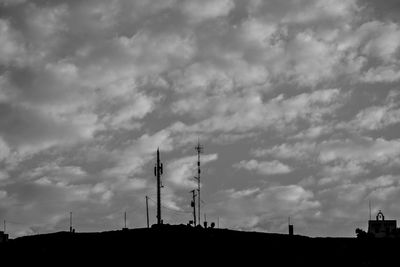 Low angle view of silhouette communications tower against sky