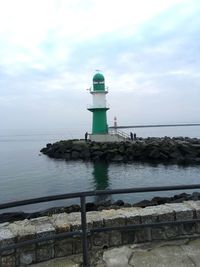 Lighthouse by sea against sky