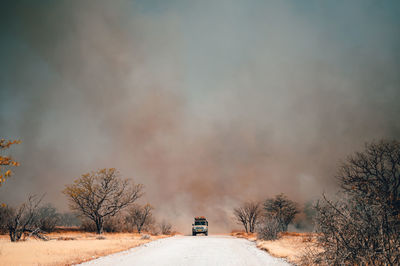 Car on dirt road against smoke