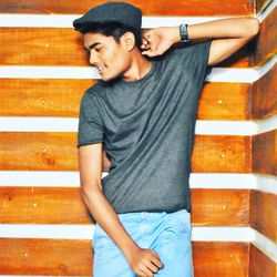 Young man looking away while standing against wall