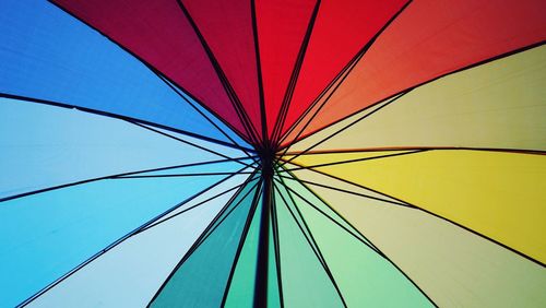 Low angle view of multi colored umbrella against blue sky