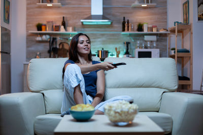 Portrait of young woman using mobile phone while sitting at home